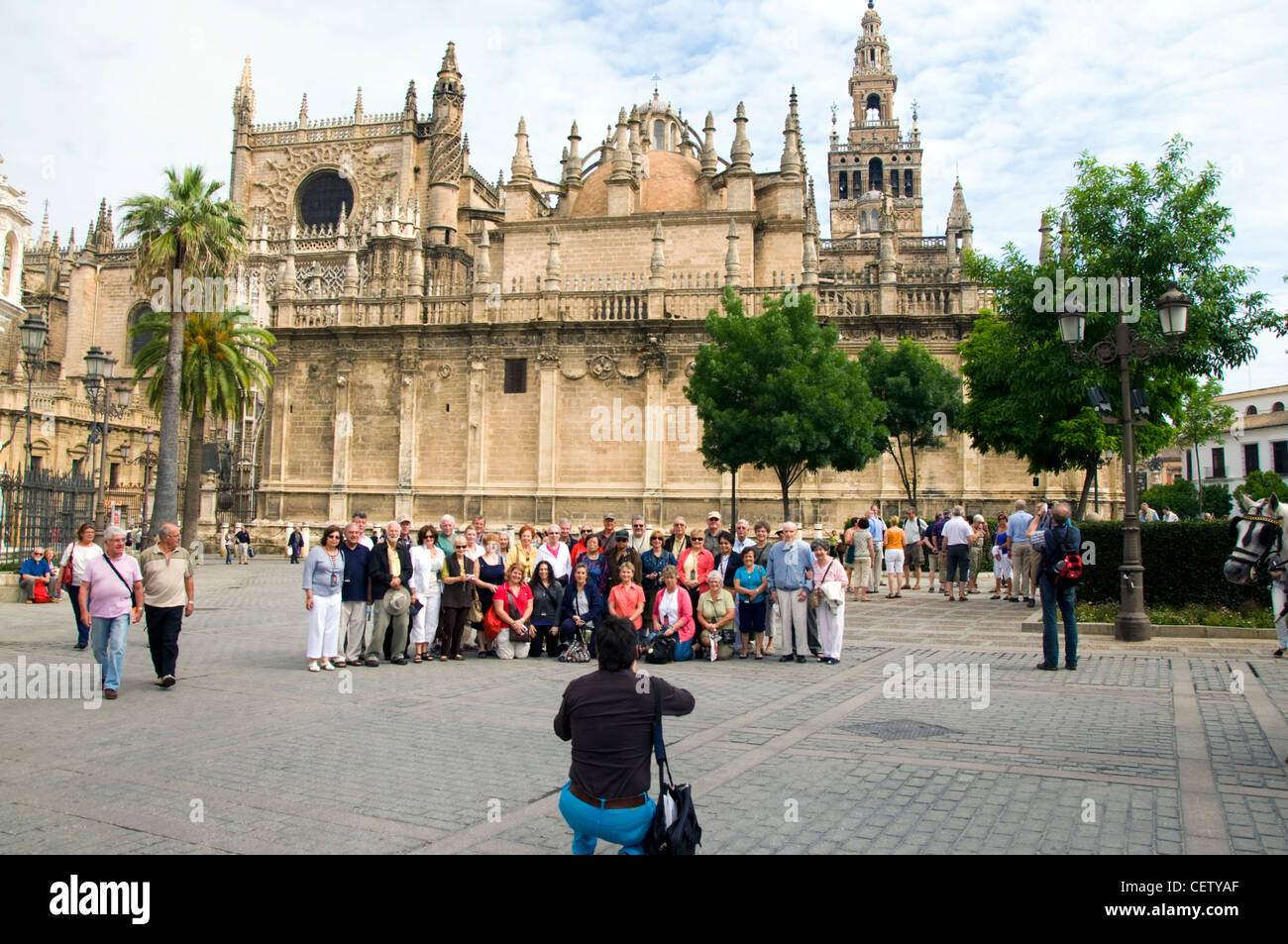 Group tour has a photograph taken by cathedral in Seville Stock Photo