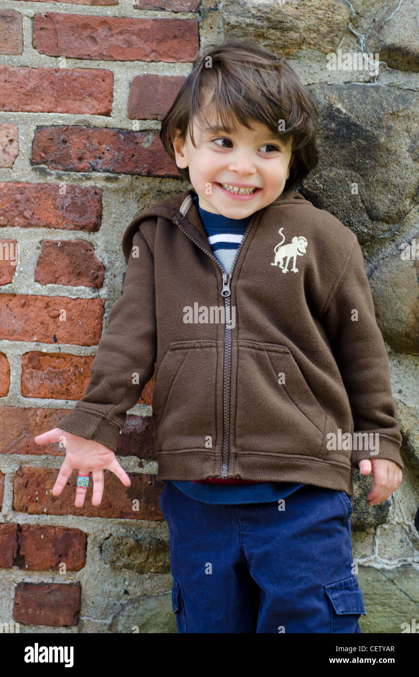 A 3-year-old standing and smiling while looking away. Stock Photo