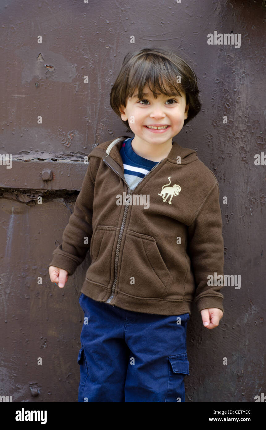 A 3-year-old standing and smiling while looking away. Stock Photo