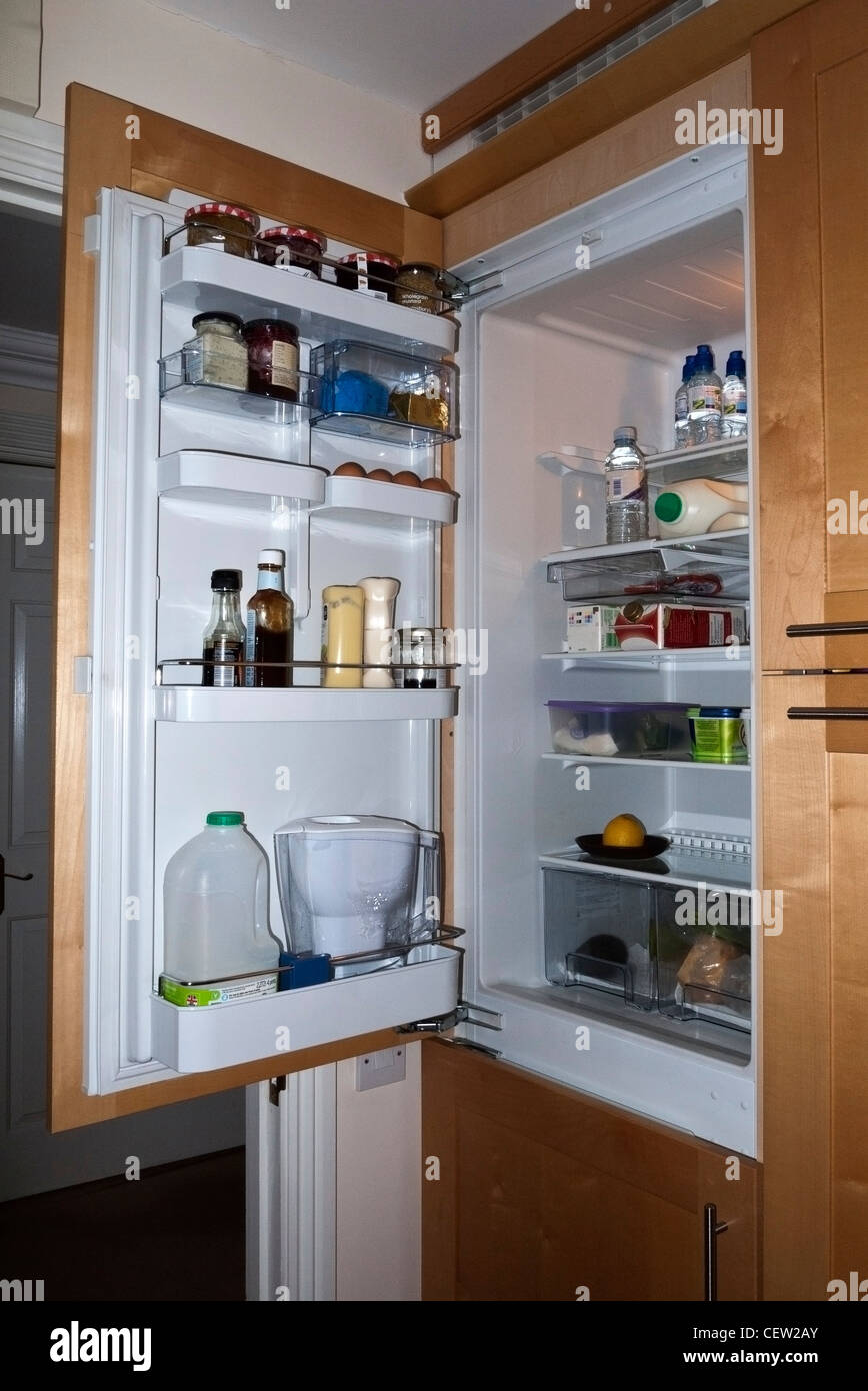 A Fridge upright cabinet with its door open showing food items on the shelves Stock Photo