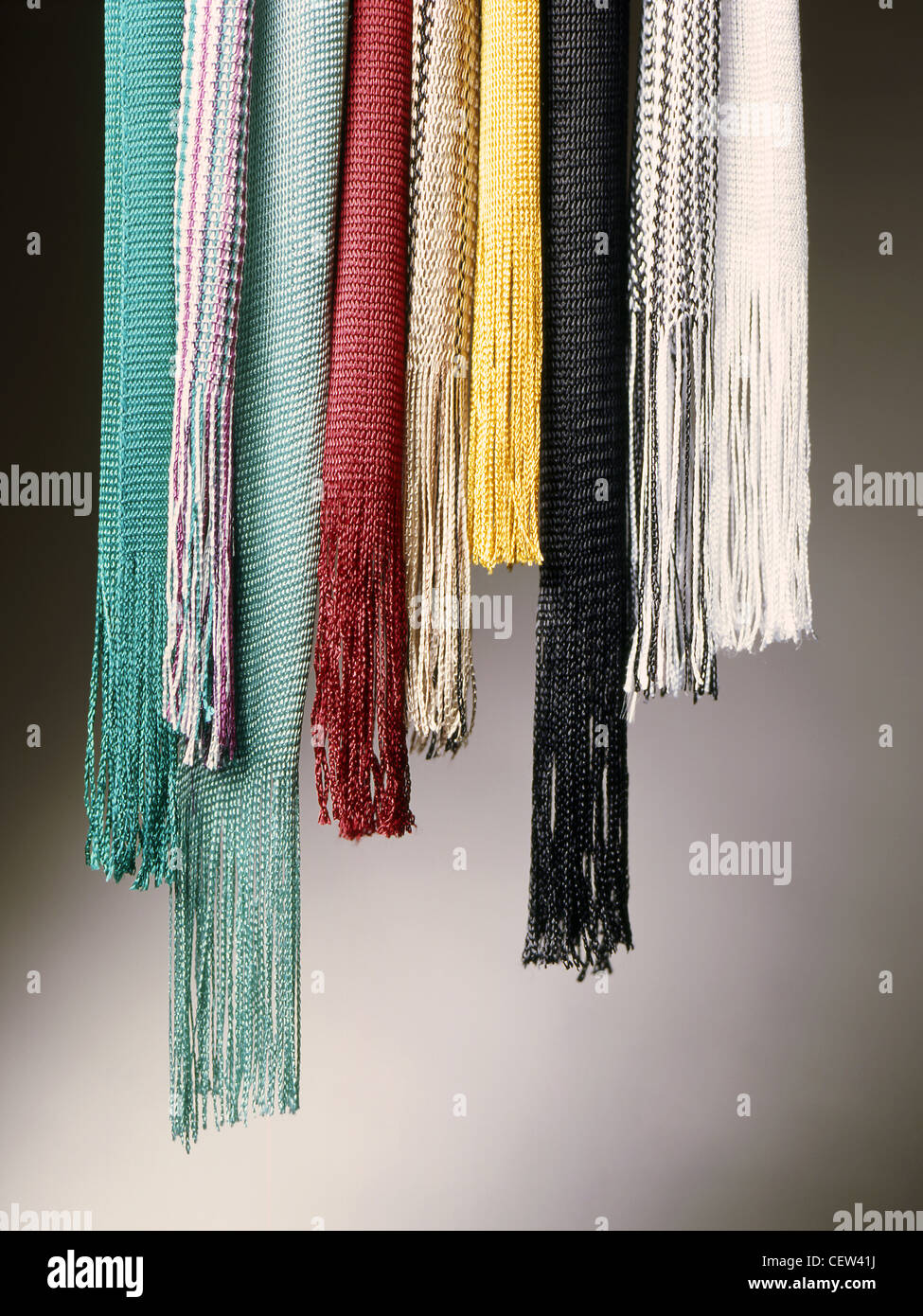 A still life shot of colourful wool scarves lined up on a salmon coloured background Stock Photo