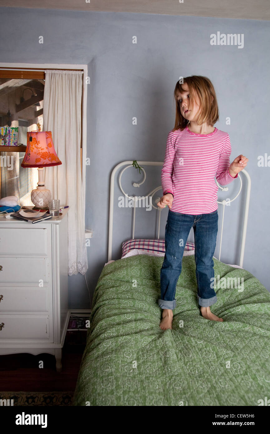 Seven year old girl stands proudly o her bed snapping her fingers to