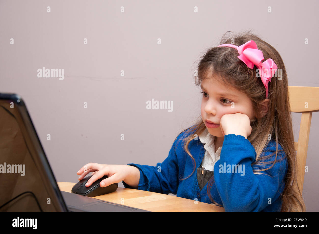 Five year old girl in Primary school uniform using a laptop computer. Stock Photo