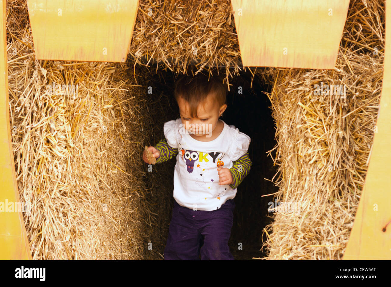 Small child walking out of hay fort Stock Photo