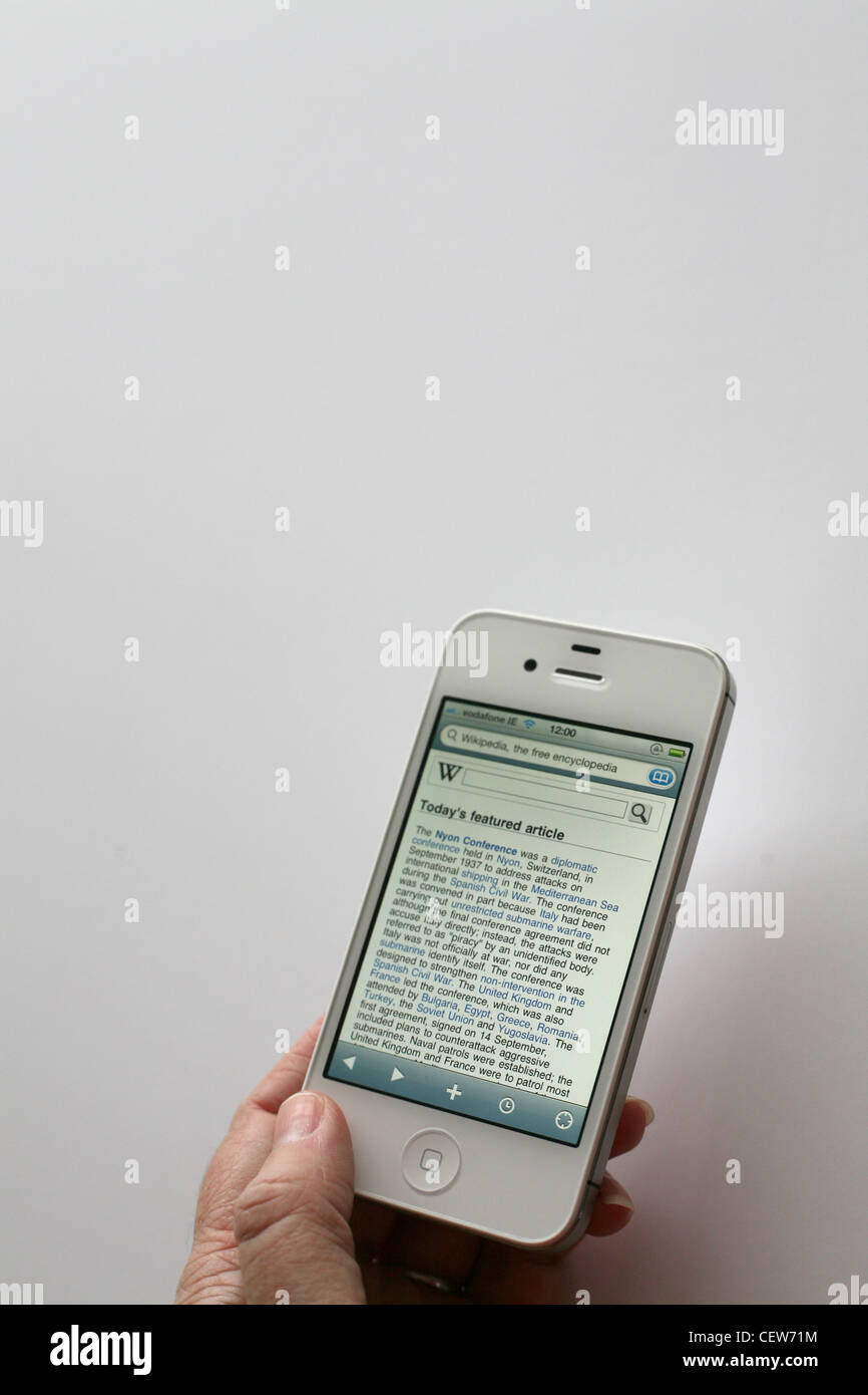 Person using a white iPhone 4s to read wikipedia Stock Photo