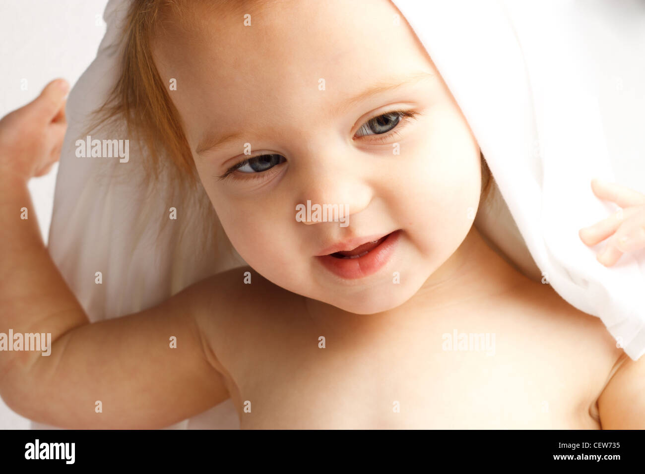 Adorable baby peeking out of a white sheet Stock Photo