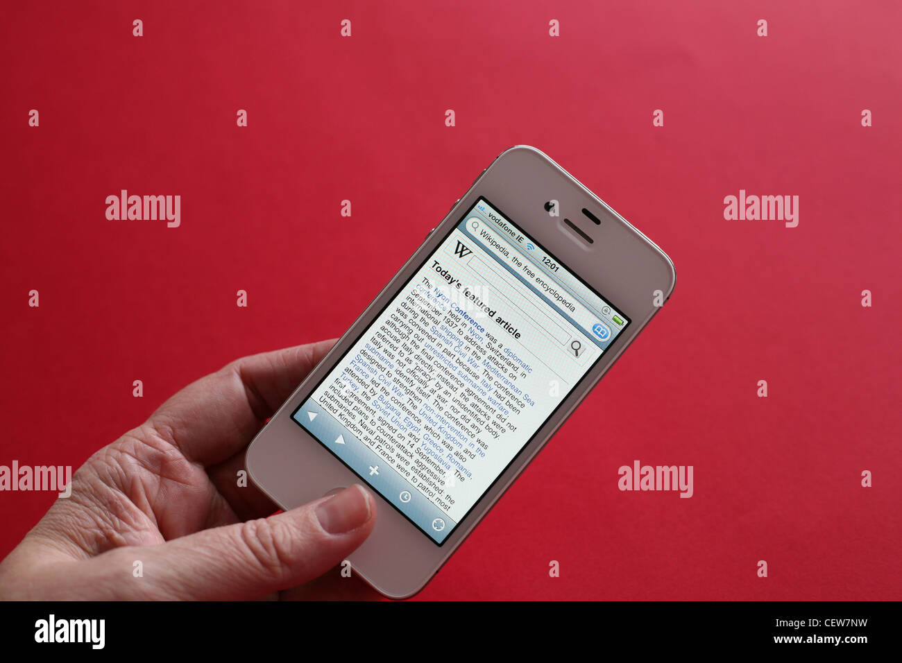 Person using a white iPhone 4s to read wikipedia Stock Photo