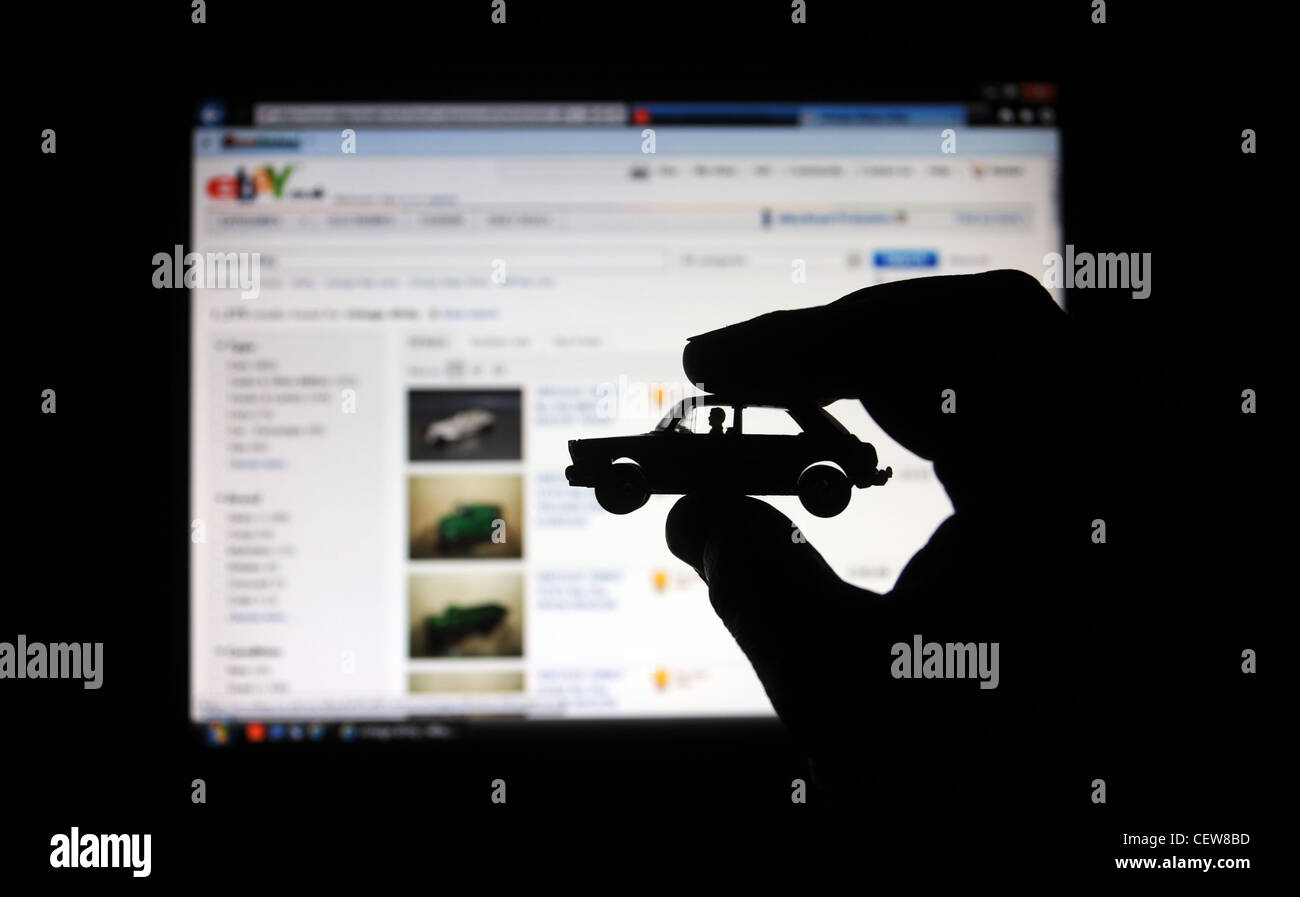 MODEL CAR HELD IN MANS HAND WITH COMPUTER SCREEN  WITH EBAY AUCTION SITE BEHIND RE INTERNET SHOPPING SELLING BUYING BUSINESS UK Stock Photo