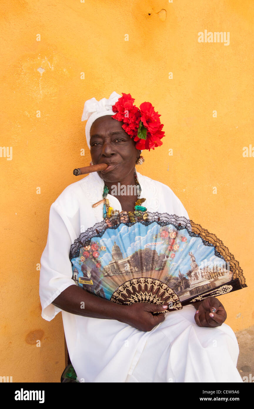Cuban woman wearing a Santeria white dress smoking a big cigar, Havana, Cuba Stock Photo