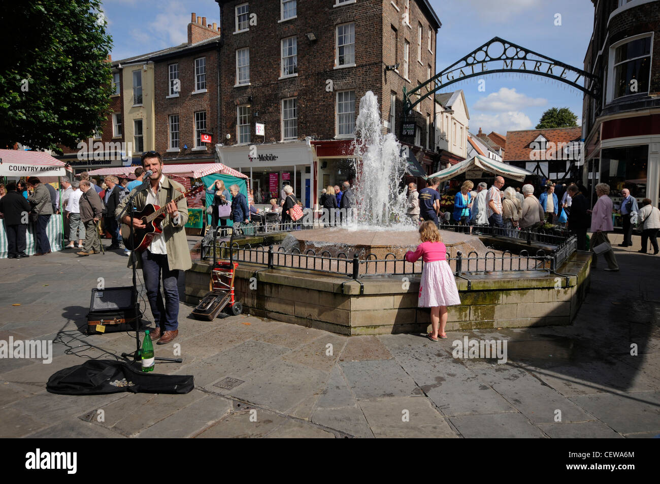Busker playing by the Parliament street fountain, York City centre. Stock Photo