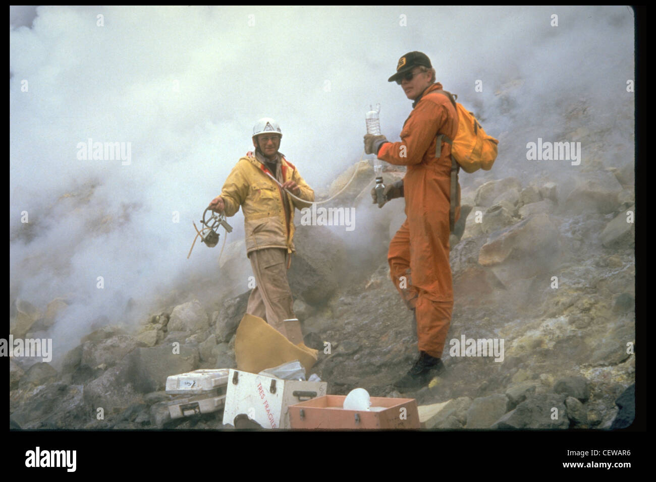 USGS geologists collect gas samples around the dome. Samples were gathered from vents on the dome and crater floor, and were used to monitor changes in chemical composition. Additionally, sulfur dioxide gas was measured from a specially-equipped airplane before, during, and after eruptions to determine 'emission rates' for the volcano. During eruptions, emission rates typically increased to 5 to 10 times their pre-eruptive value. Stock Photo