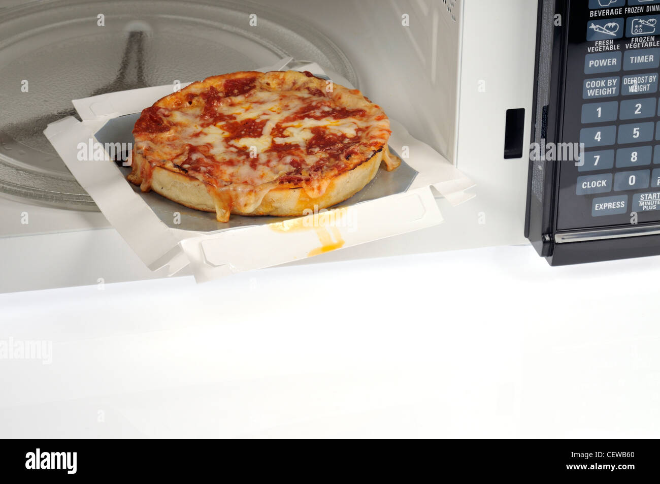 Microwave cooked single deep dish pizza with pepperoni topping in microwave oven Stock Photo