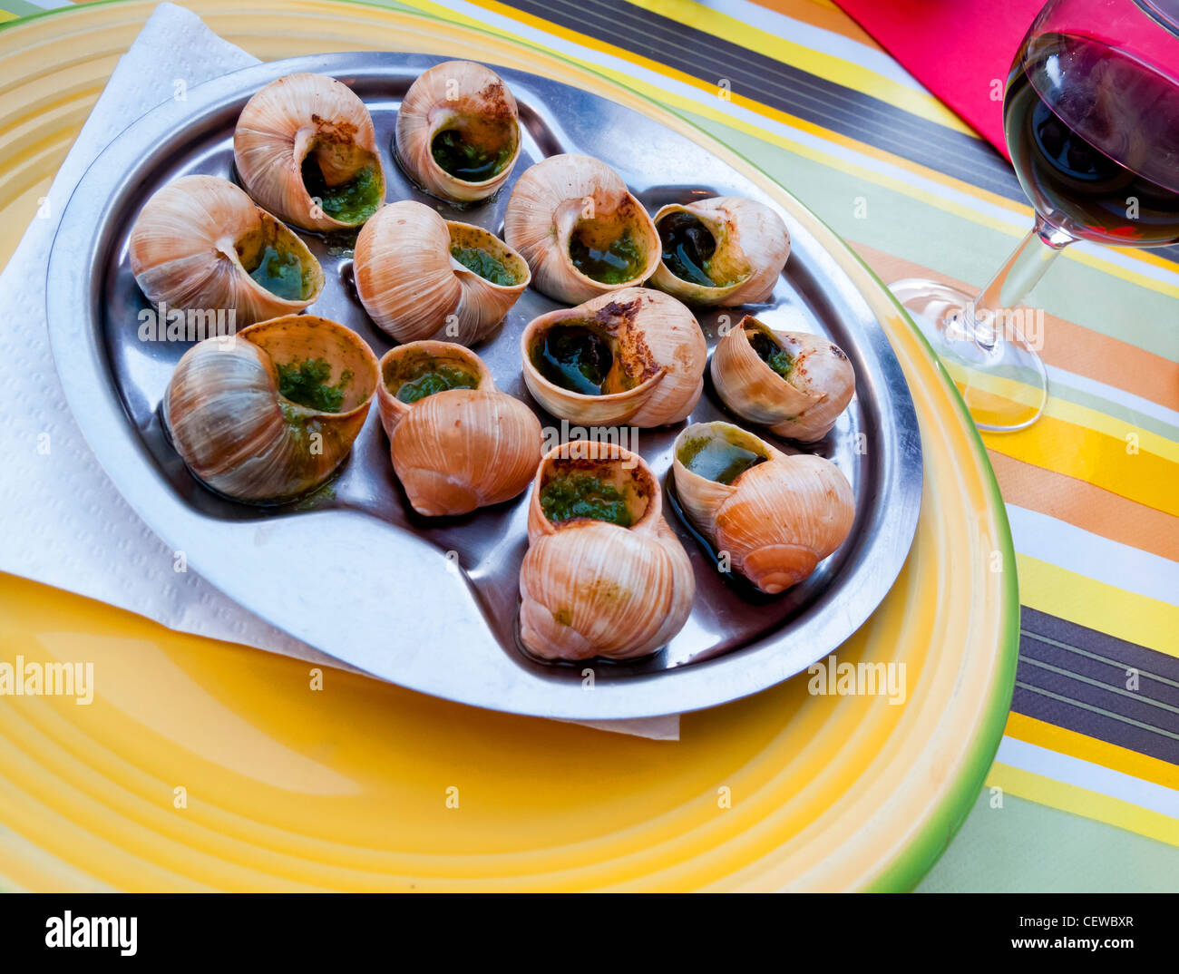 Plate of traditionally cooked snails served with garlic with a glass of red wine in a village restaurant in Savoie France Stock Photo