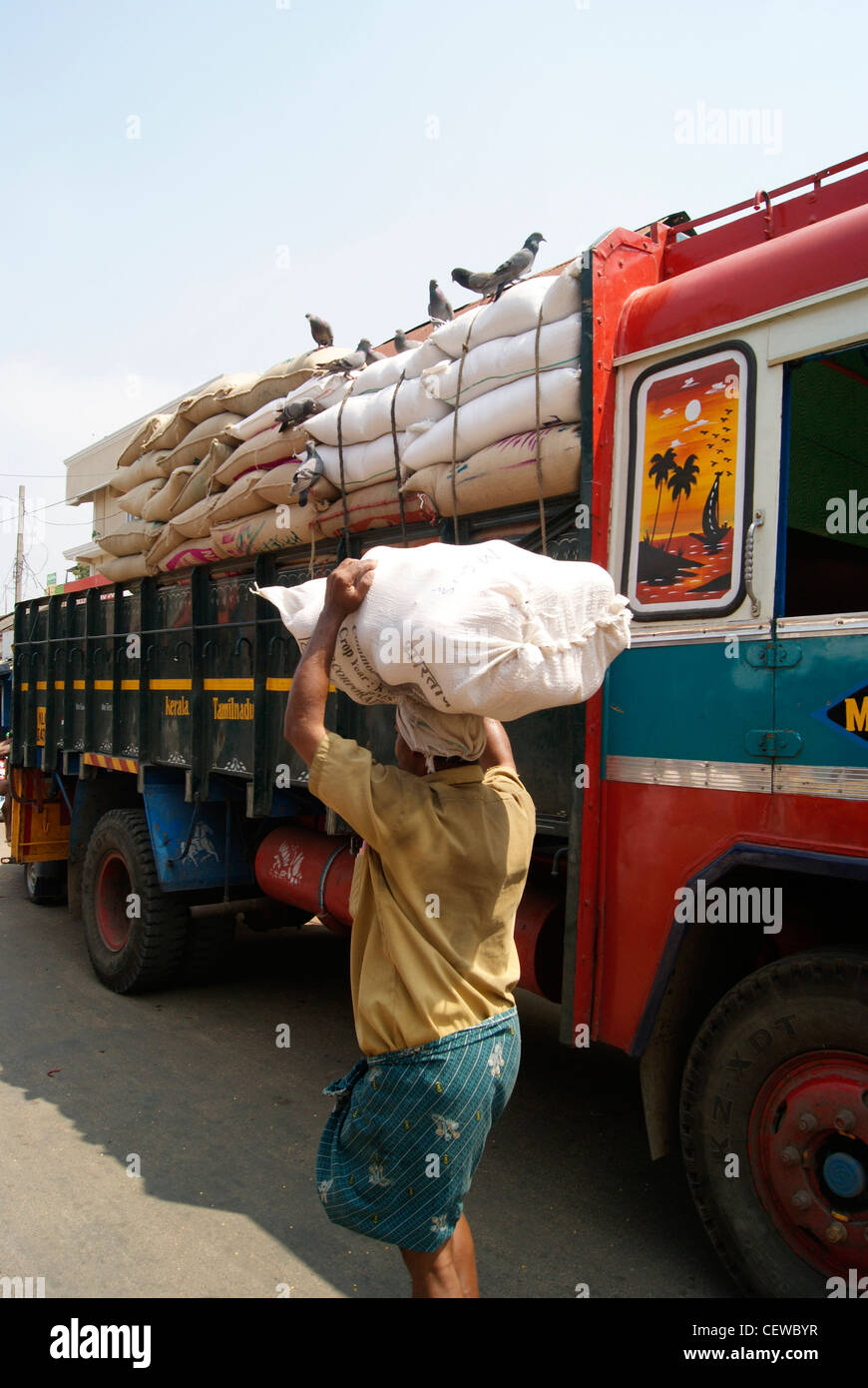 Worker Carrying Rice Sack on Head nearby Rice carrying Goods Lorry.A Chalai Market scene from Trivandrum City at Kerala,India. Stock Photo