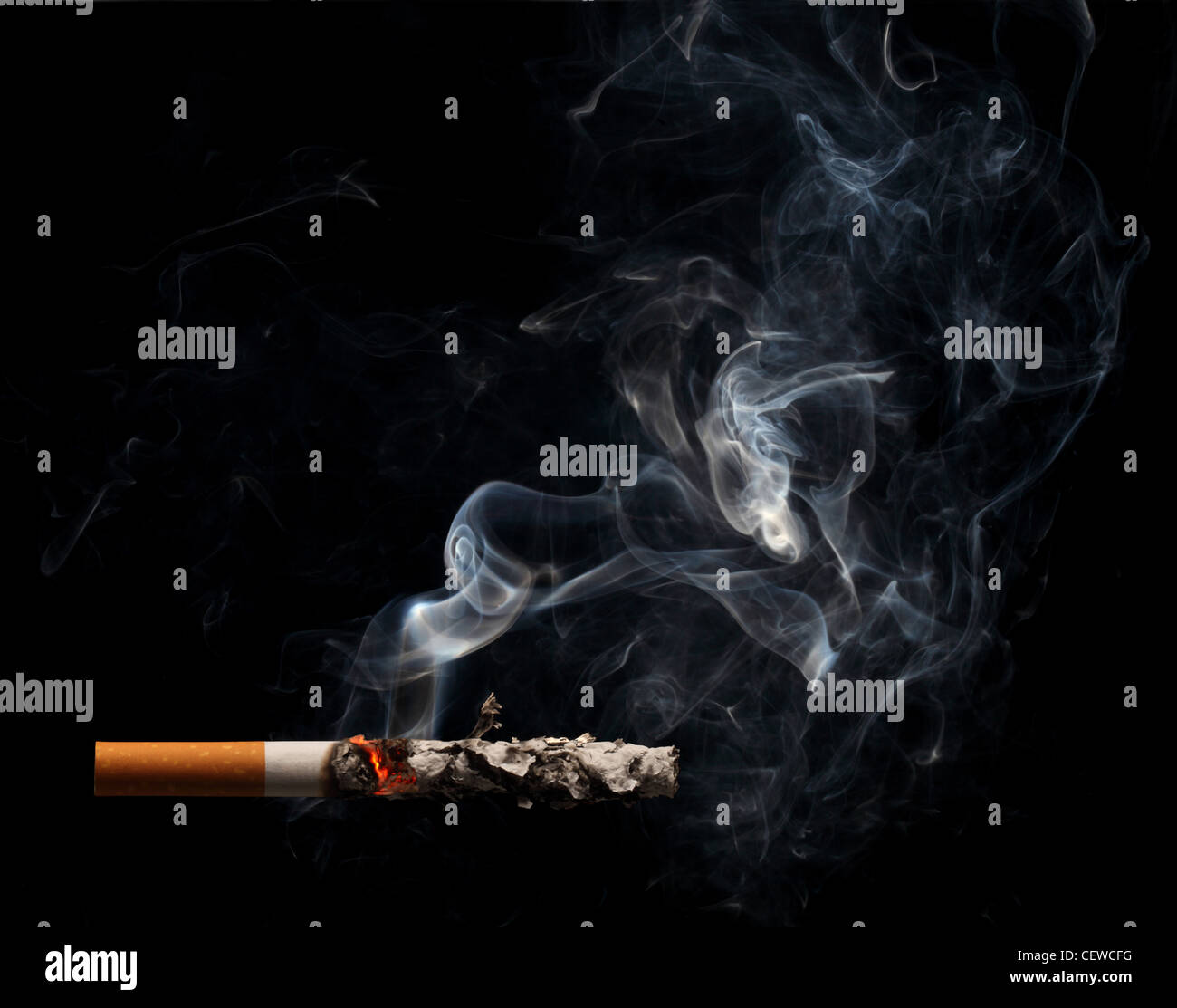 A burning and smoking cigarette on a black background Stock Photo