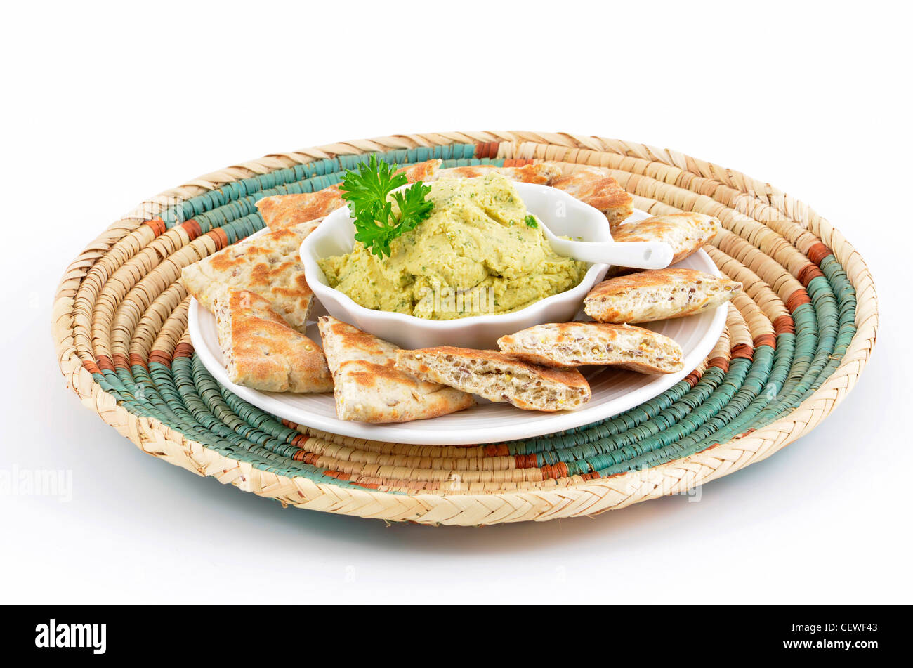 Fresh homemade hummus with pita bread triangles on decorative woven tray with white background in horizontal format Stock Photo