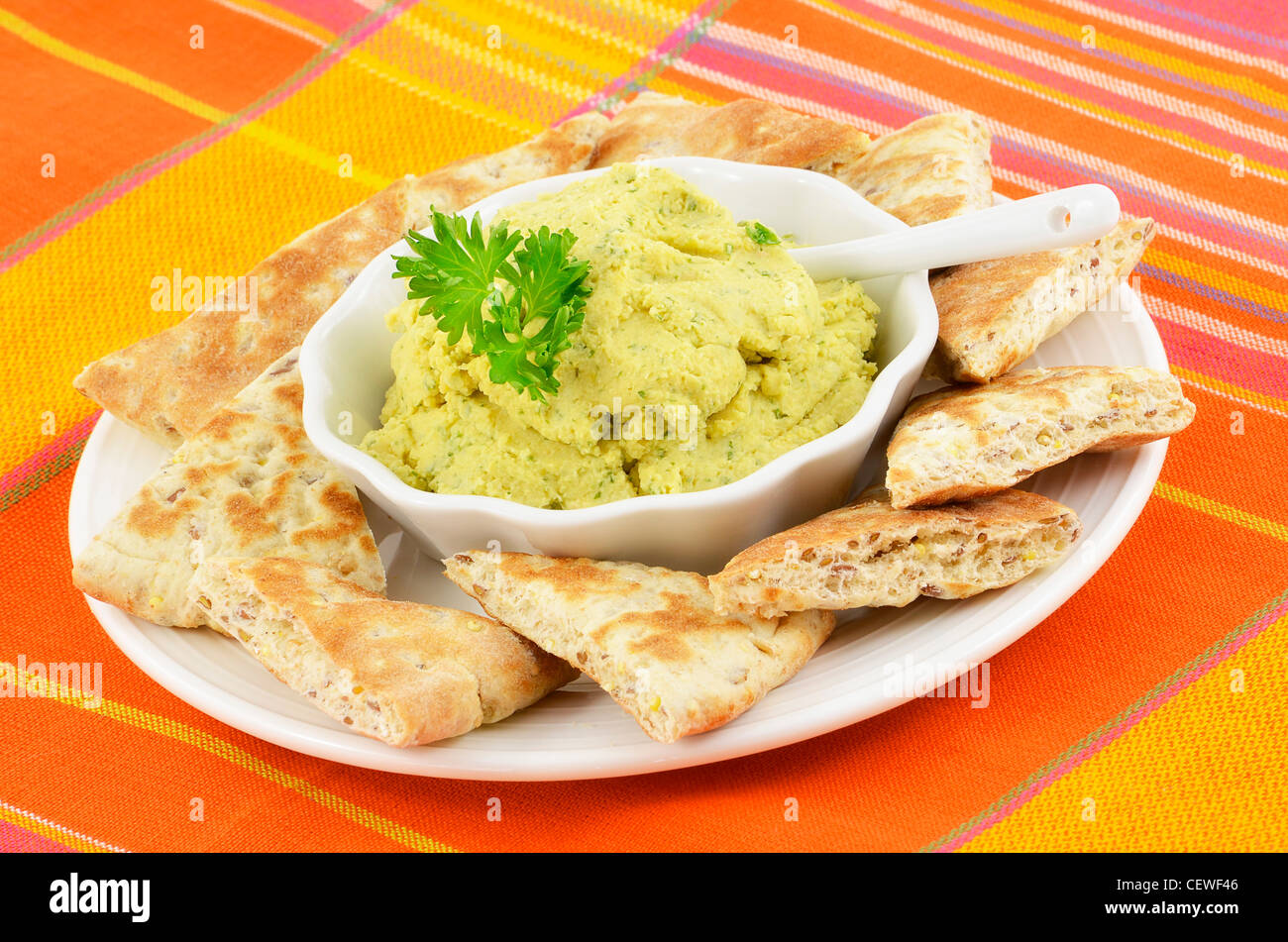 Fresh homemade hummus with pita bread triangles on decorative woven