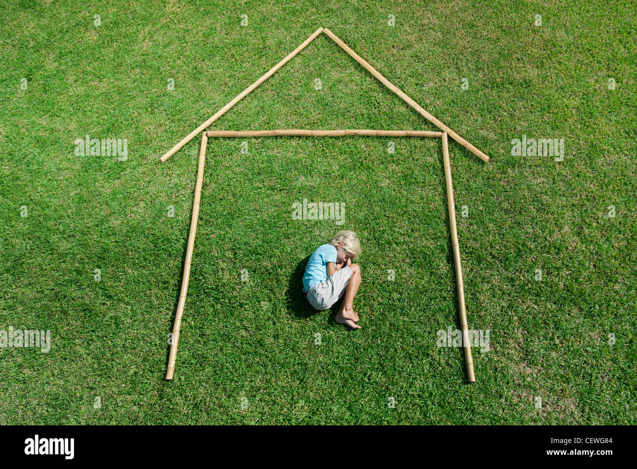 Boy in fetal position within outline of house, high angle view Stock Photo
