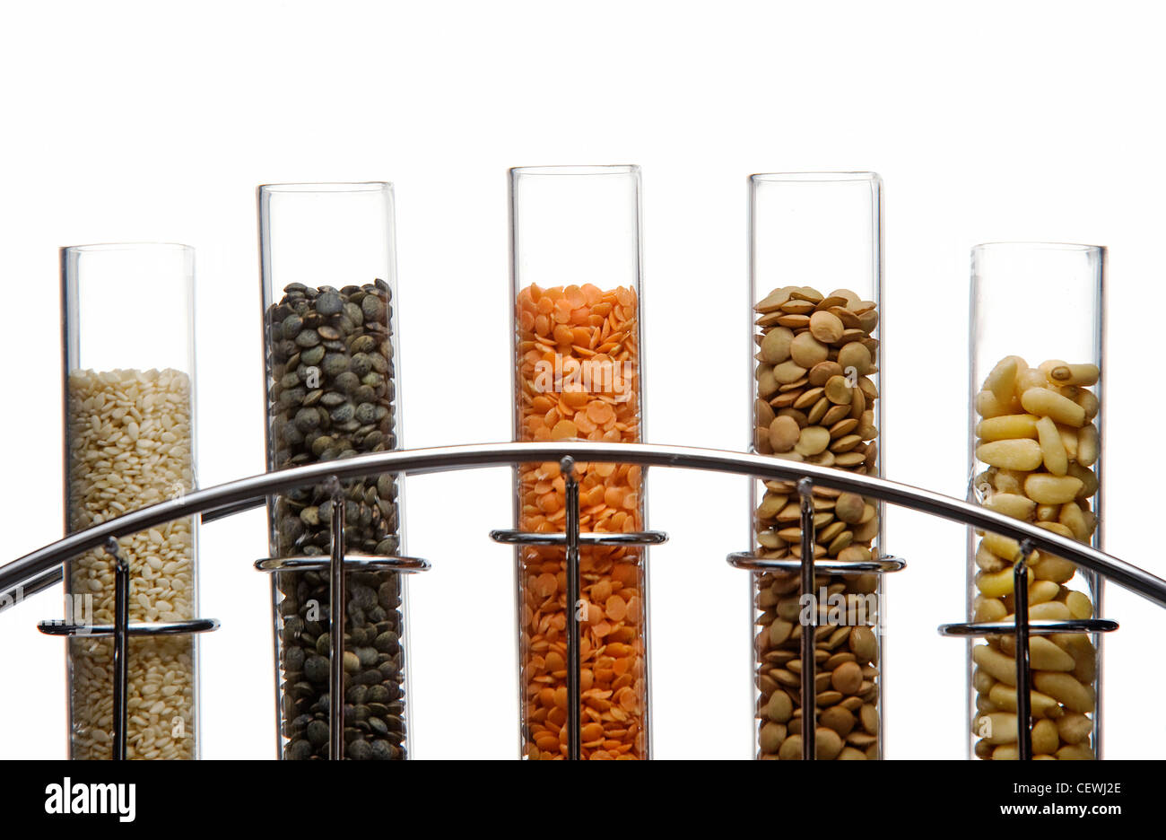 Sesame seeds, Puy lentils, split red lentils, brown lentils and pine nuts in glass test tubes in a chrome stand Stock Photo