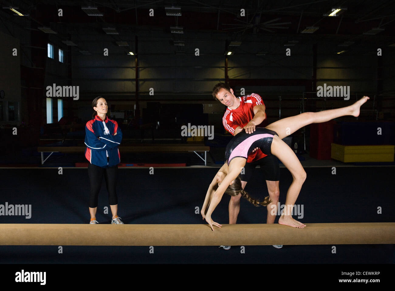 Female gymnast practicing on balance beam with coach Stock Photo