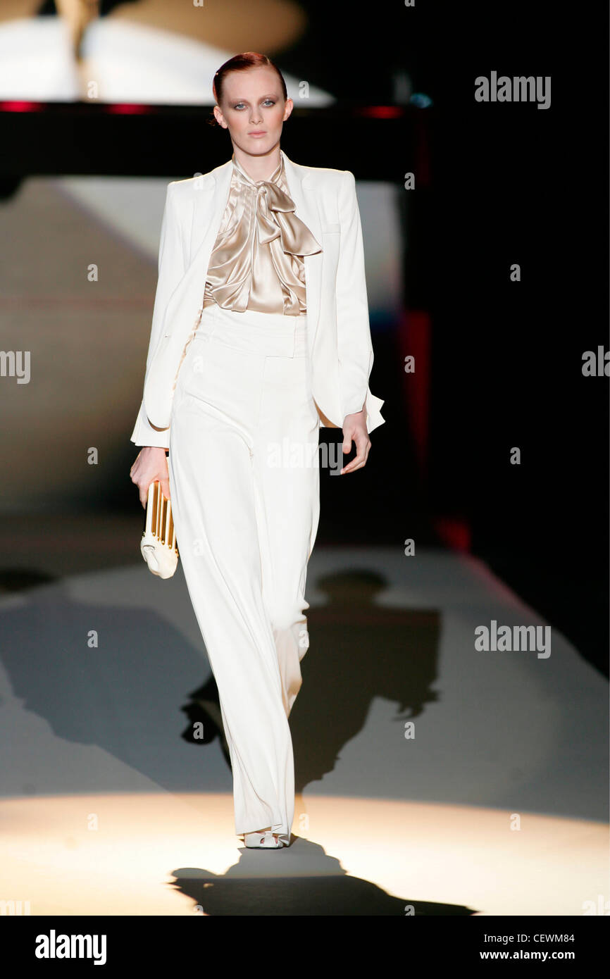 British model Karen Elson wearing white trouser suit and brown satin blouse with necktie; her hair off face Stock Photo