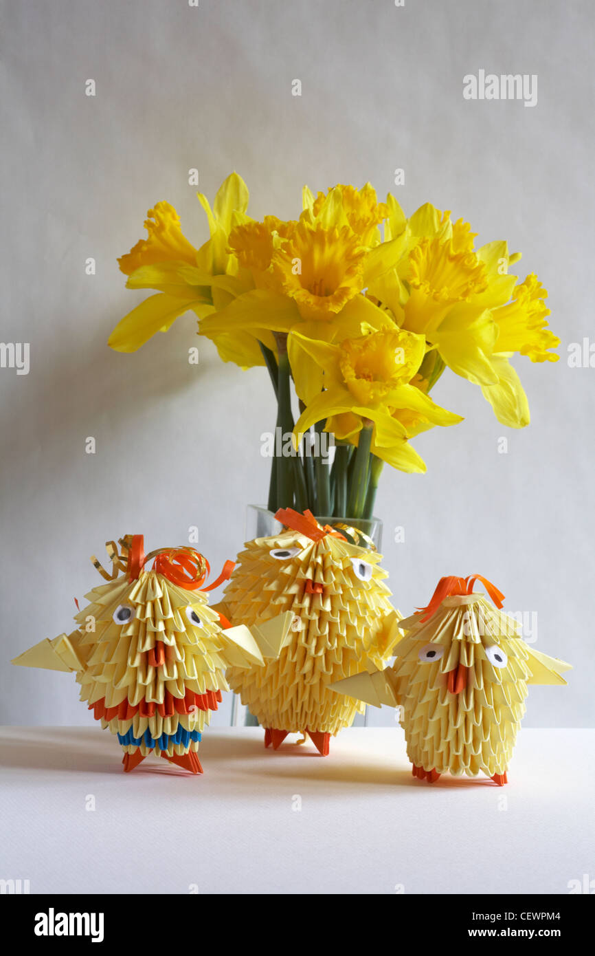 Family of Easter Origami chicks with vase of daffodils isolated on white background Stock Photo