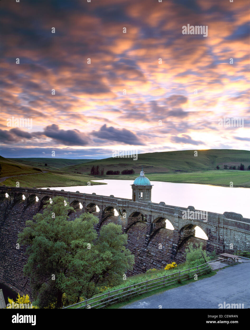 Parting storm clouds create a dramatic sky as the sun sets over Craig Goch dam and reservoir in the Elan Valley. Stock Photo