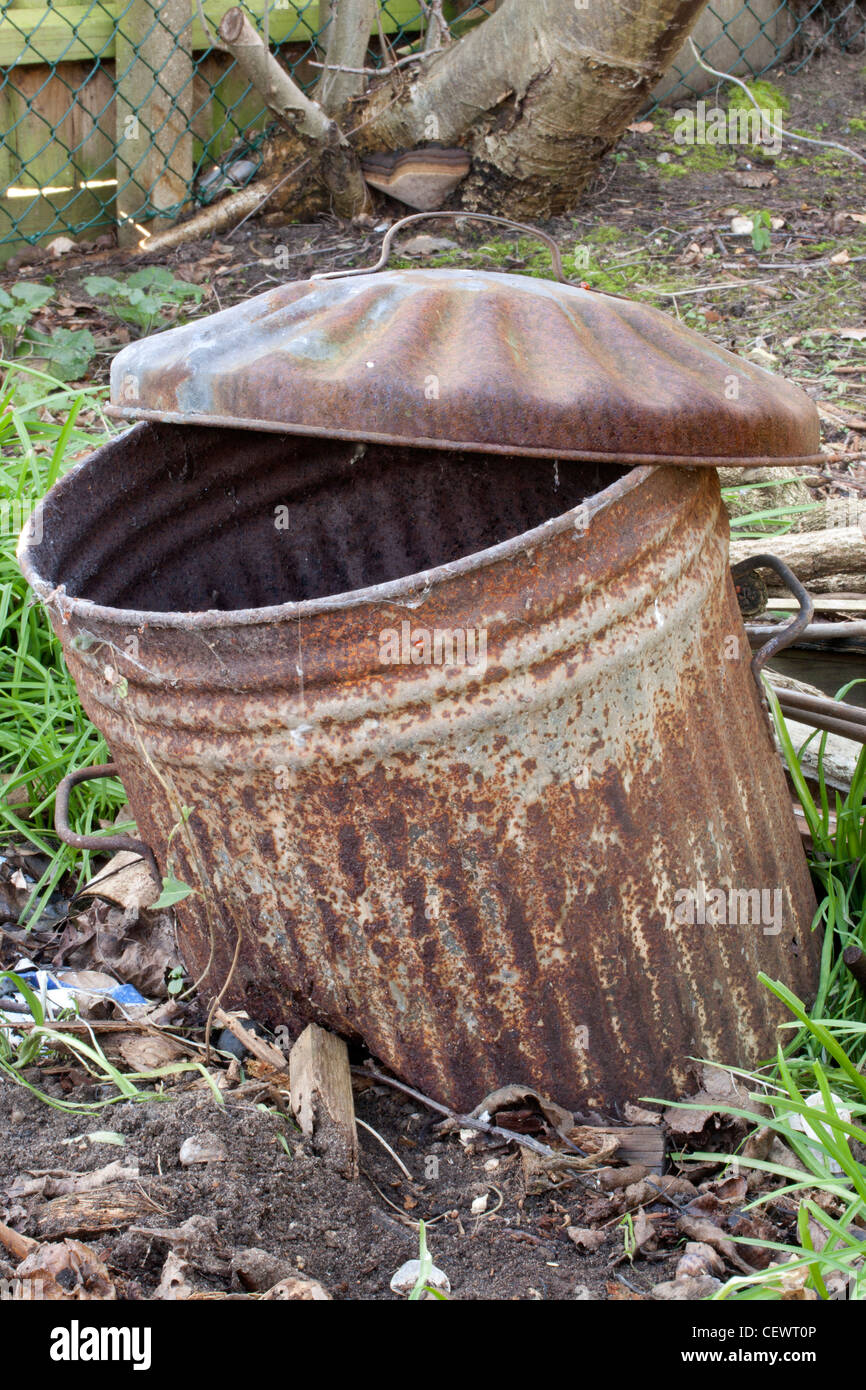Abandoned rusty old trashcan half buried in the ground Stock Photo