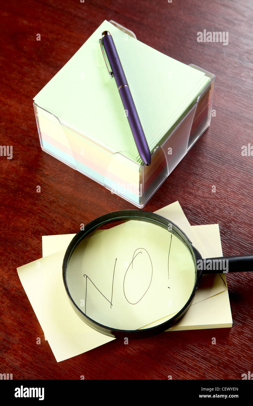 Magnifier and pile of stickers with an inscription "no" on a table ...