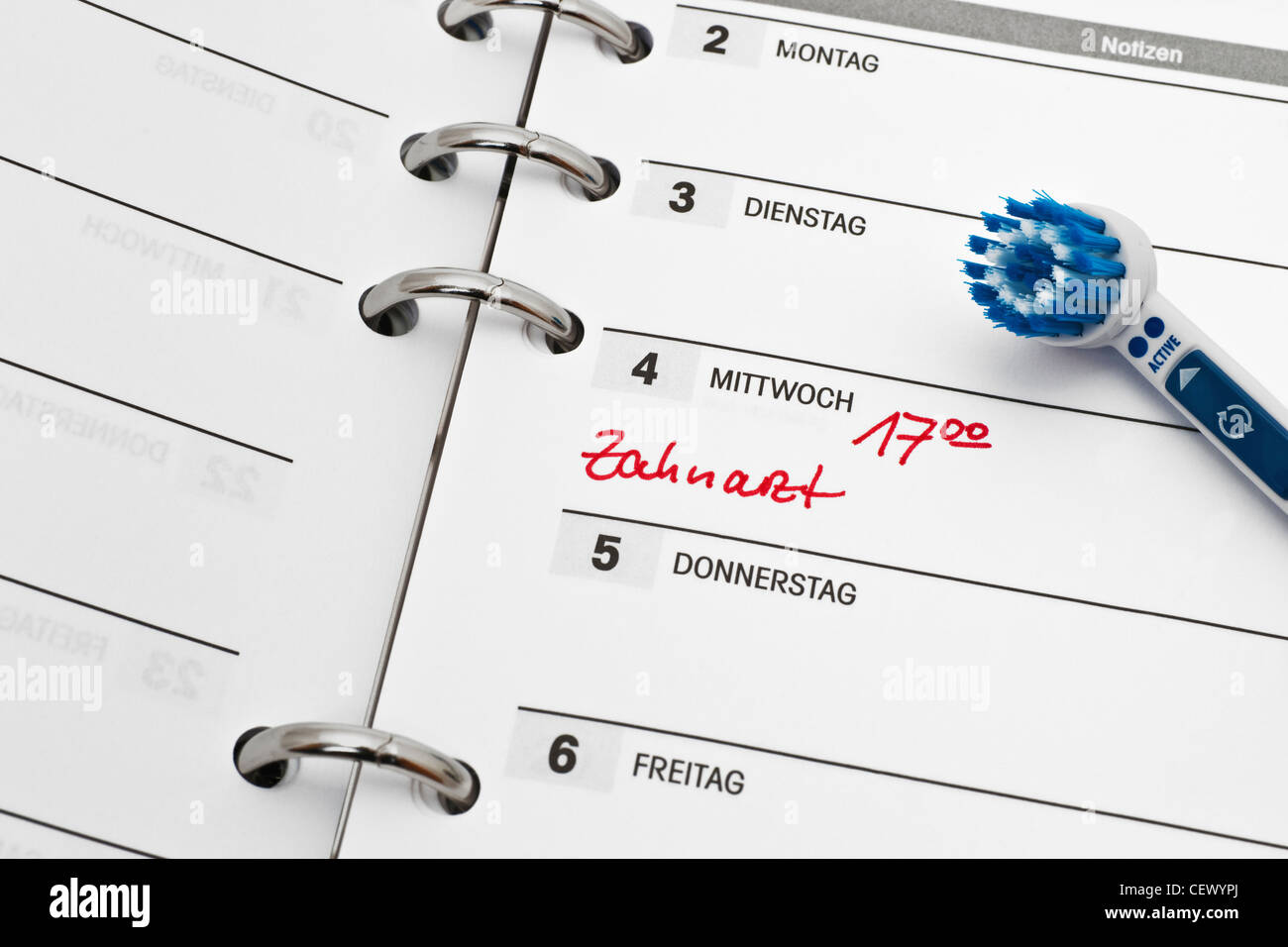 Detail photo of a calendar with a dentist appointment, a toothbrush alongside, German language Stock Photo