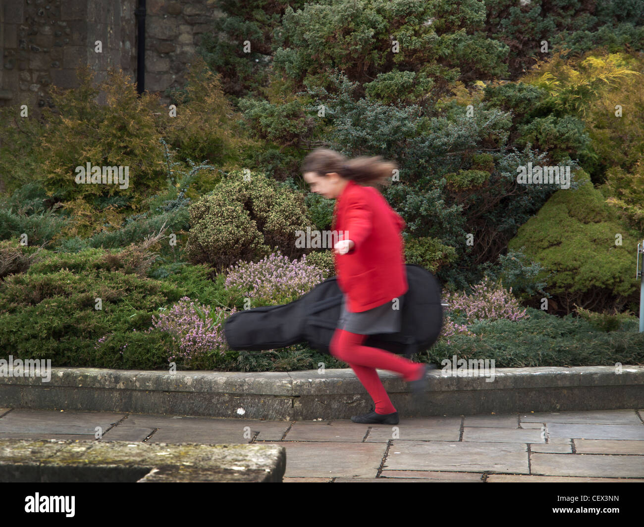 A school child runs through the gardens of Chichester Cathedral Stock Photo
