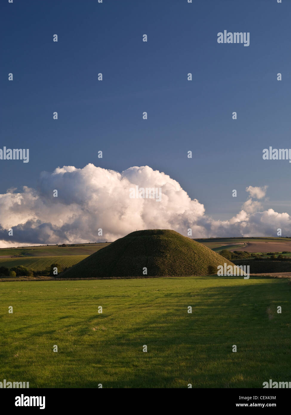 View of Silbury Hill, the tallest prehistoric human-made mound in Europe, against a bank of cloud on a clear evening. Stock Photo