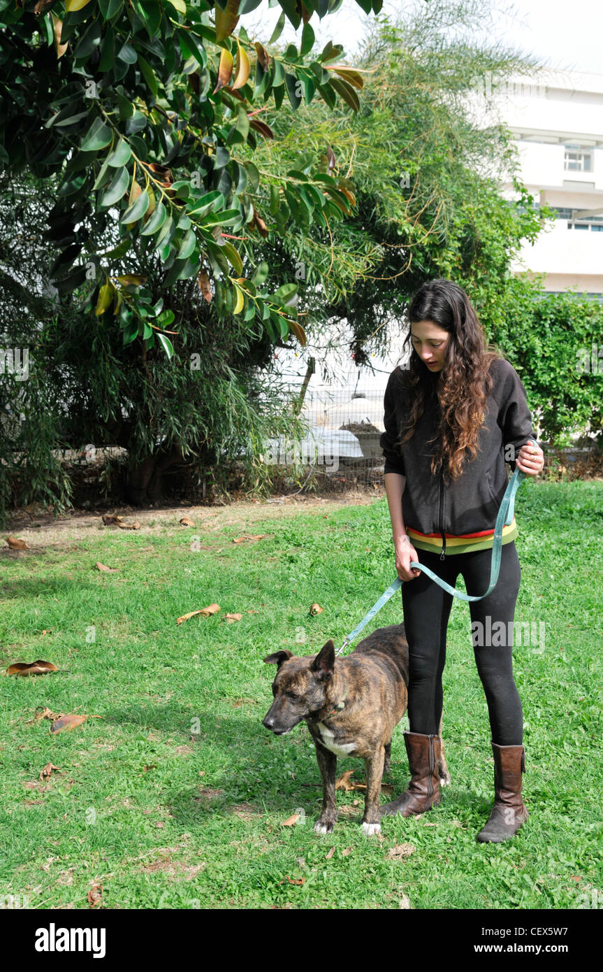 Young woman walks her dog in an urban park Stock Photo