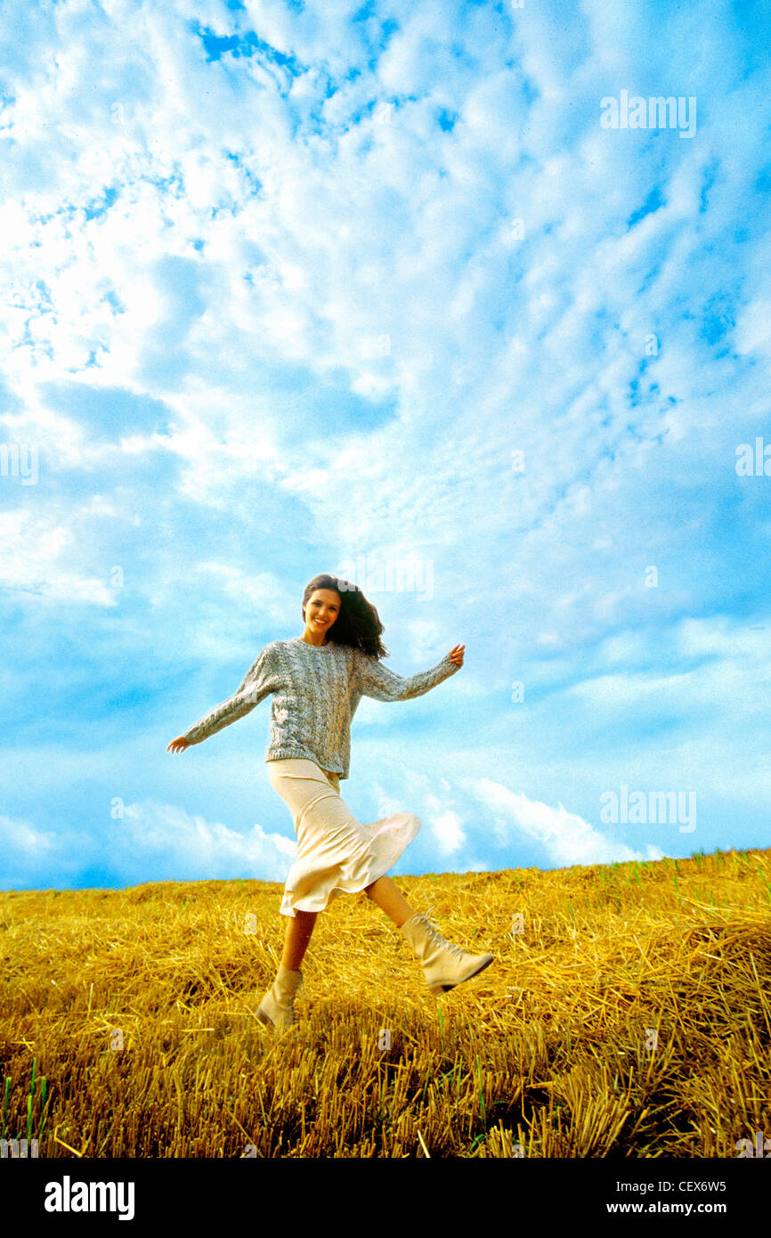 Female walking in field kicking leg up in front of her Stock Photo