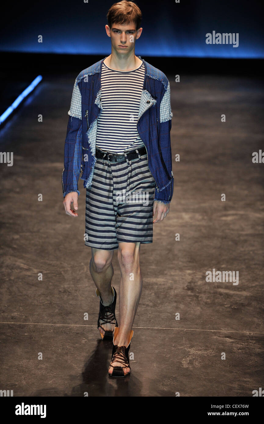 Blaak Paris Menswear Spring Summer Model wearing grey striped shorts, black and white striped top, blue denim patchwork jacket, Stock Photo