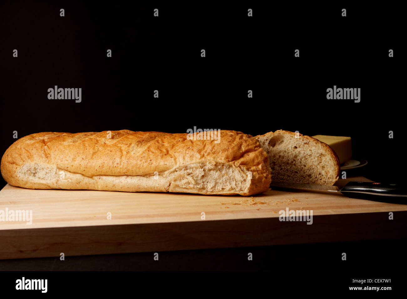 Cutting board with wheat bread, butter and bread knife Stock Photo