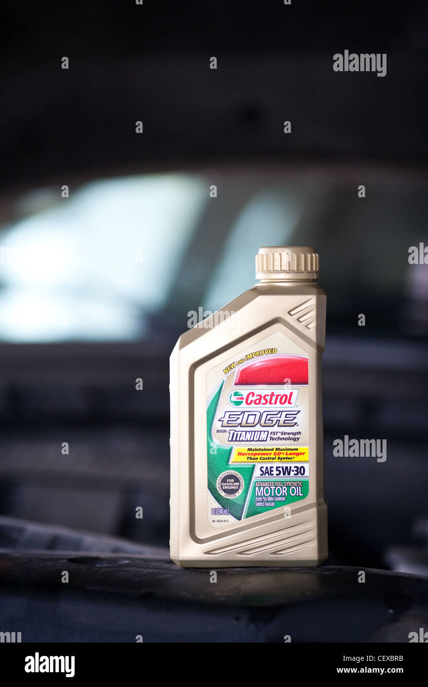 A bottle of motor oil sitting on the edge of a vehicle engine compartment. Stock Photo