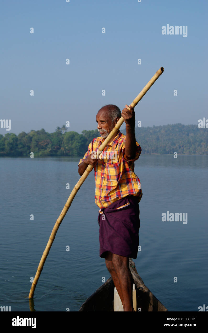 Kerala traditional canoe boat man sailing using bamboo stick staying in