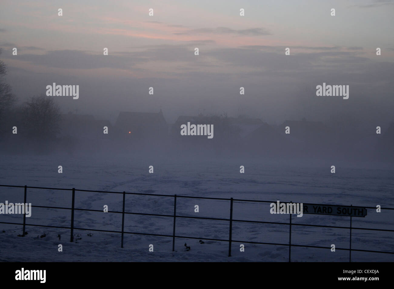 Snow and fog sunrise over field and roofs Minster Yard South Beverley early morning pink sky winter Stock Photo