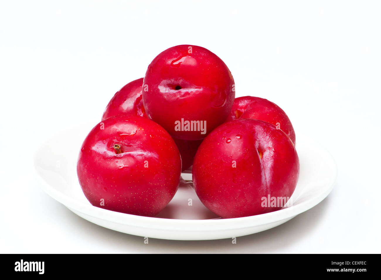 Fresh plums in white plate on white background Stock Photo