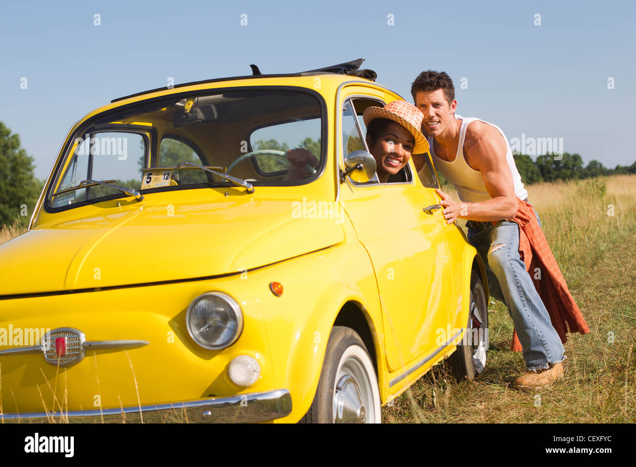 Man pushing girlfriend in broken down car Stock Photo