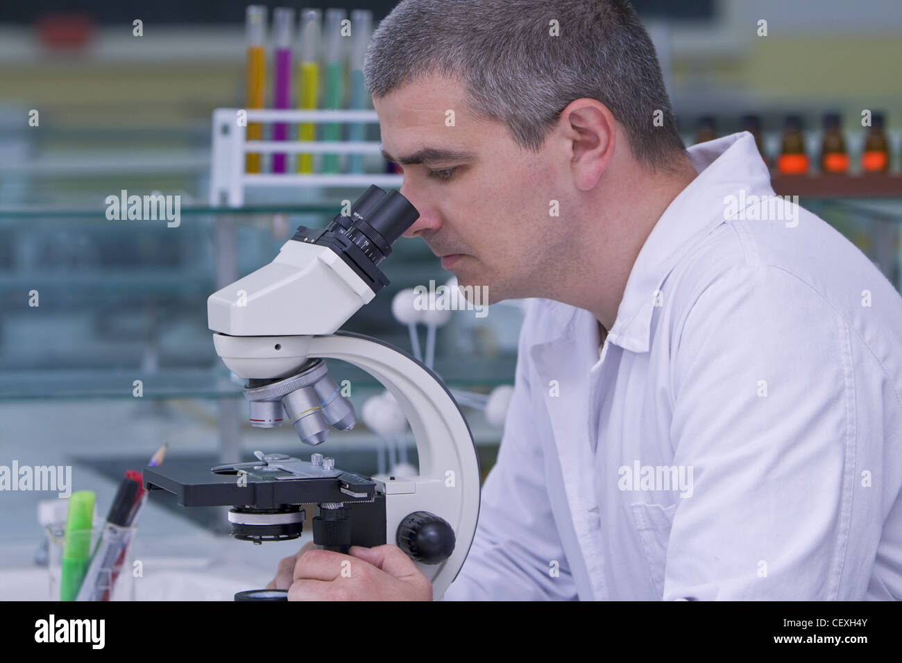 Male researcher looking through a microscope in a laboratory. Stock Photo