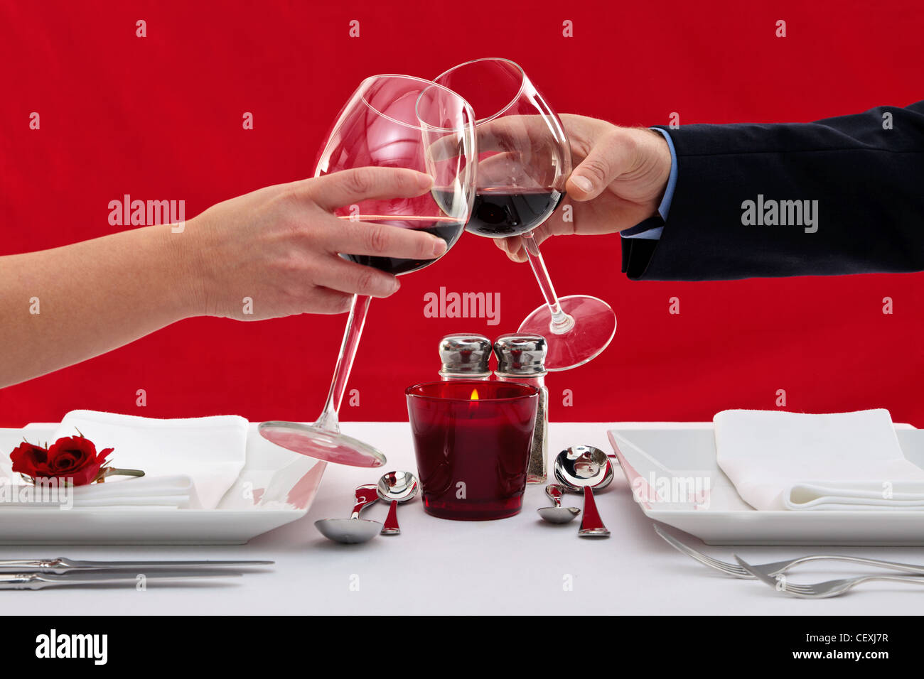 Photo of the hands of a married couple toasting their wine glasses over a restaurant table during a romantic dinner. Stock Photo