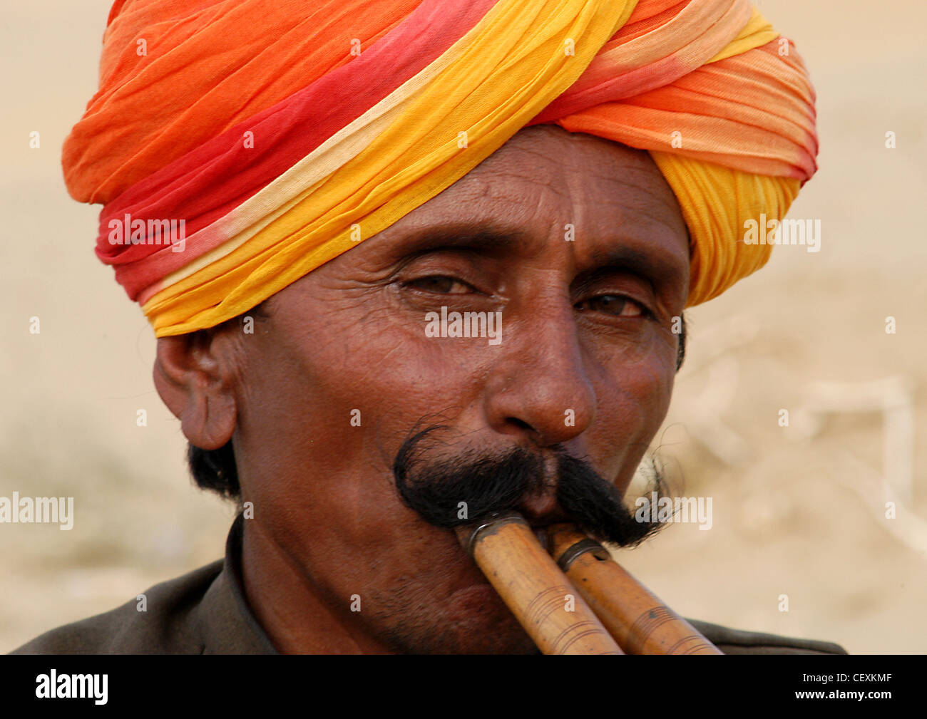 Rajput man with mustache playing unique classical music remarkably with two flutes entertaining tourists in Rajasthan desert. Stock Photo