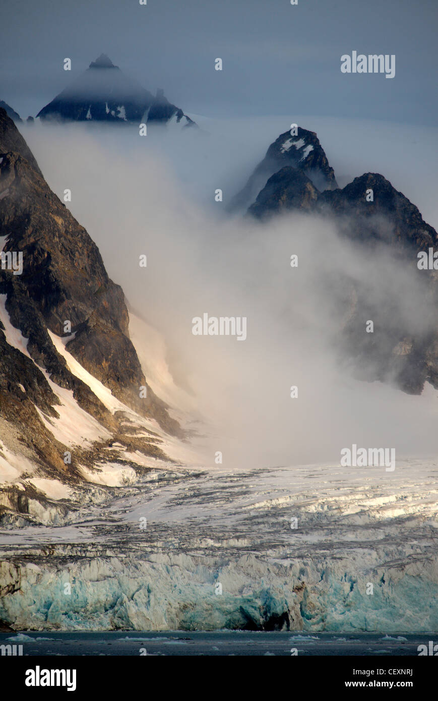 Mountain landscape with glacier, low sun and fog, N-W Svalbard, Norway Stock Photo