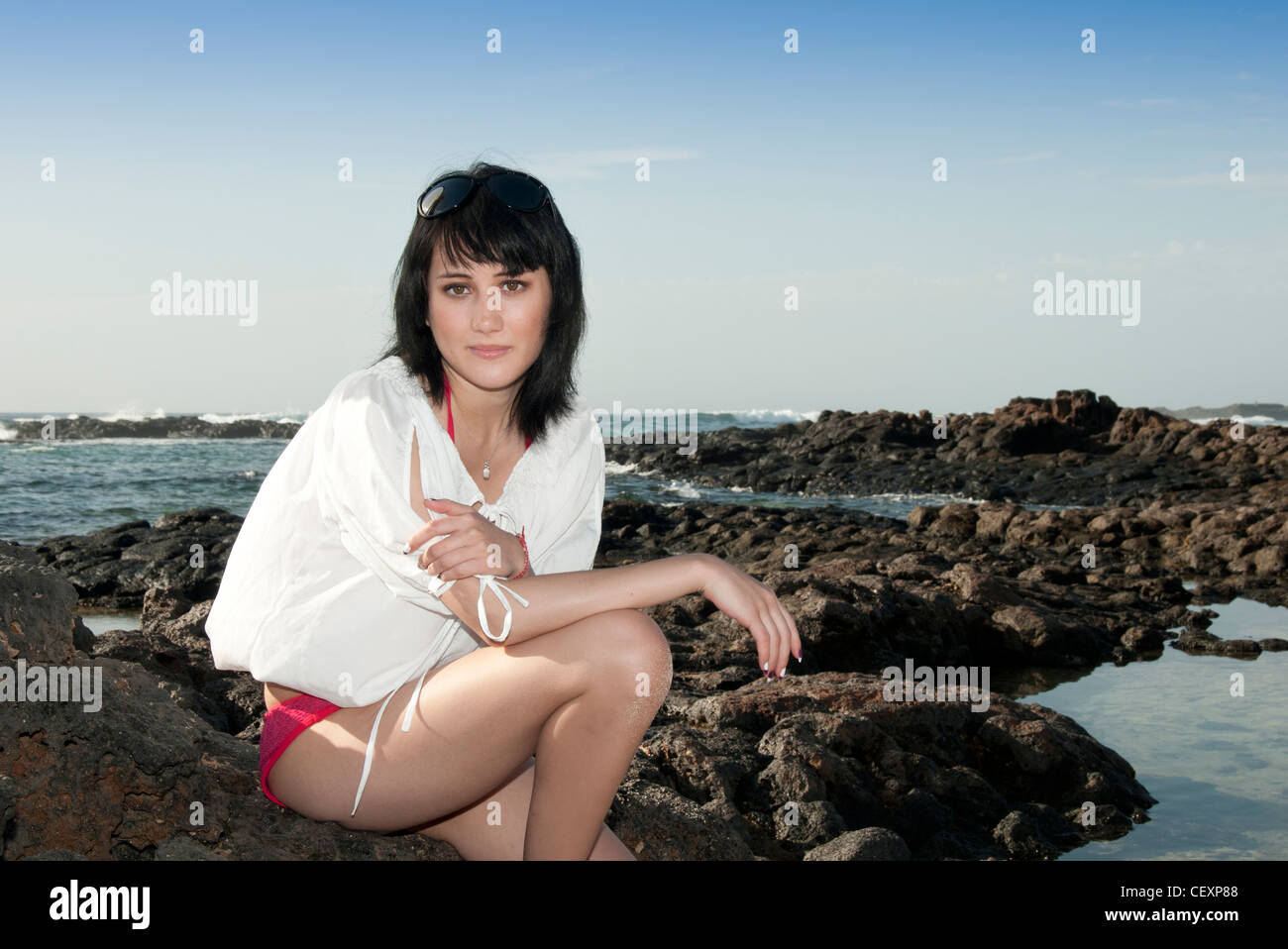 young woman sitting on the rocks thinking Stock Photo - Alamy