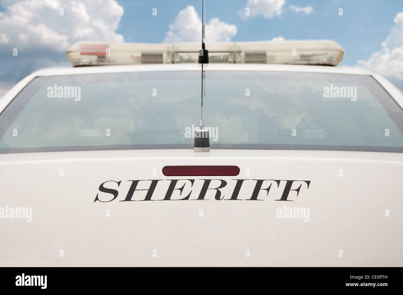 Rear end of a sheriff's patrol car with cloudy sky background Stock Photo