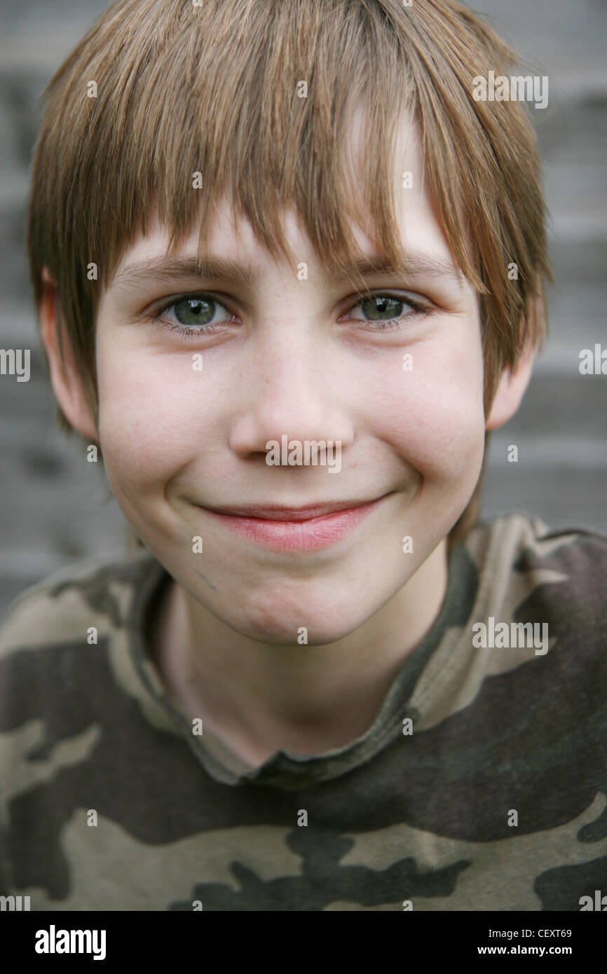 A preteen male wearing a camoflage patterned t shirt, smiling and looking to camera Stock Photo