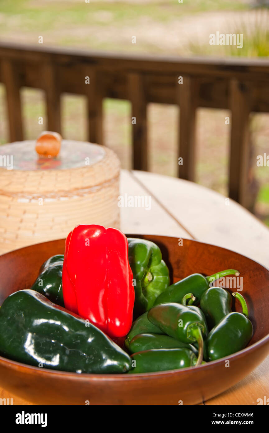Wooden bowl filled with different kinds of chili peppers and tortilla warmer in background Stock Photo