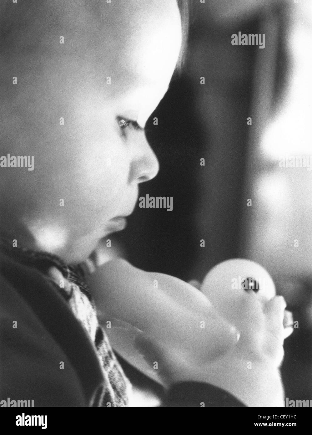 'FACES OF ALFI' Profile of baby playing with toy rubber duck serious expression Stock Photo